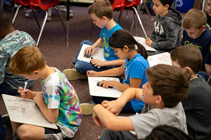 School children sitting on the floor doing their work