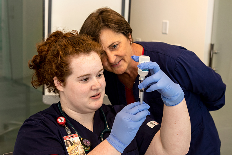 A student works with a member of the faculty in the simulation lab