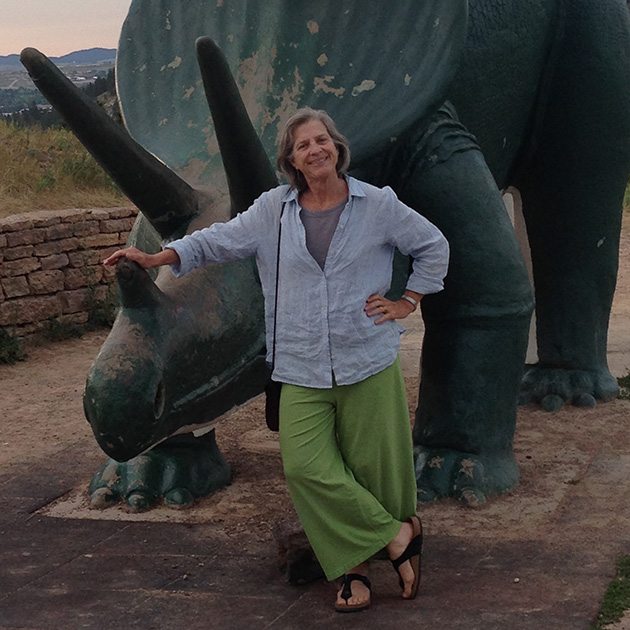 artist Sarah Perkins poses with a statue of a triceratops