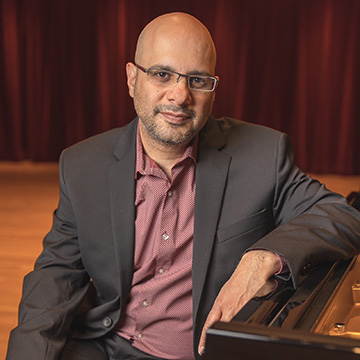 Pianist Dror Birar poses onstage with a piano