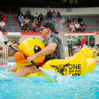 Male riding yellow duck in pool