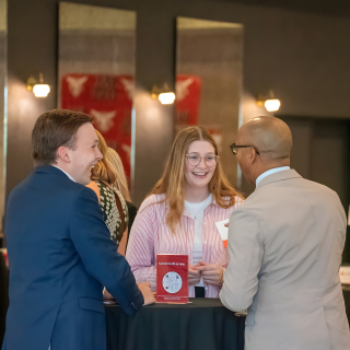 Two men and women networking at a table at an event.