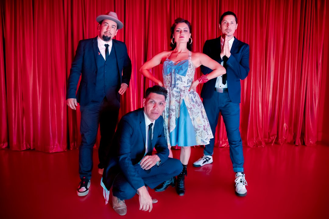 Las Cafeteras pose in front of a red curtain
