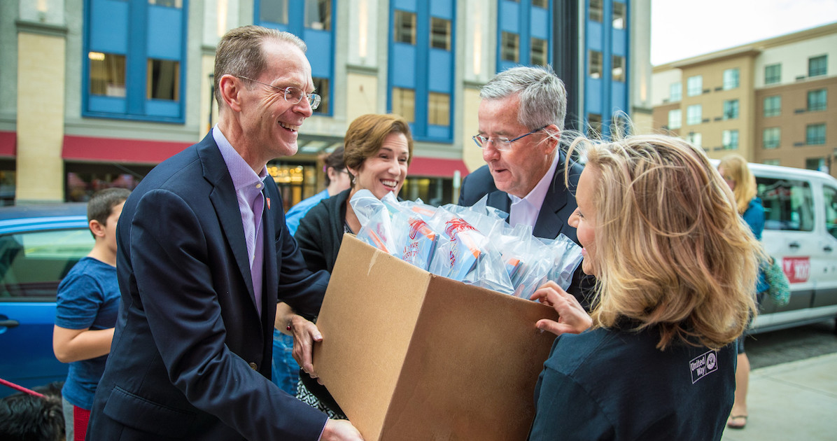 President Mearns and Jennifer Mearns hand boxes of items to people