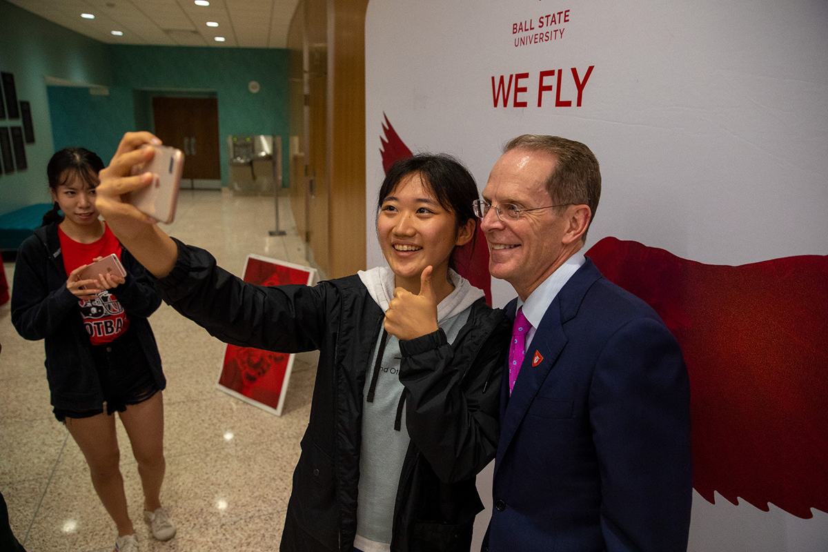 President Mearns takes a selfie in front of "We Fly" sign
