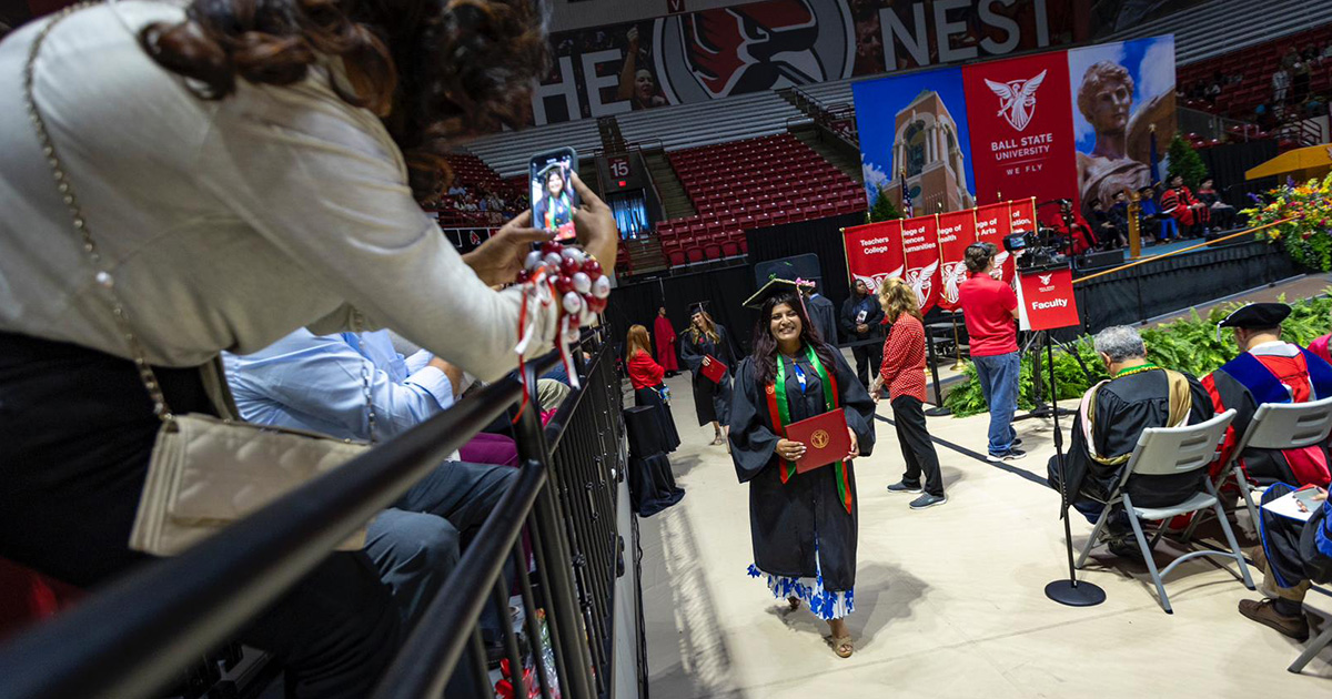 Graduate getting their photo taken by a loved one after receiving their diploma
