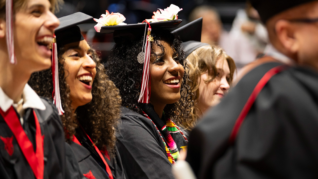 Several students smiling and listening to speaker