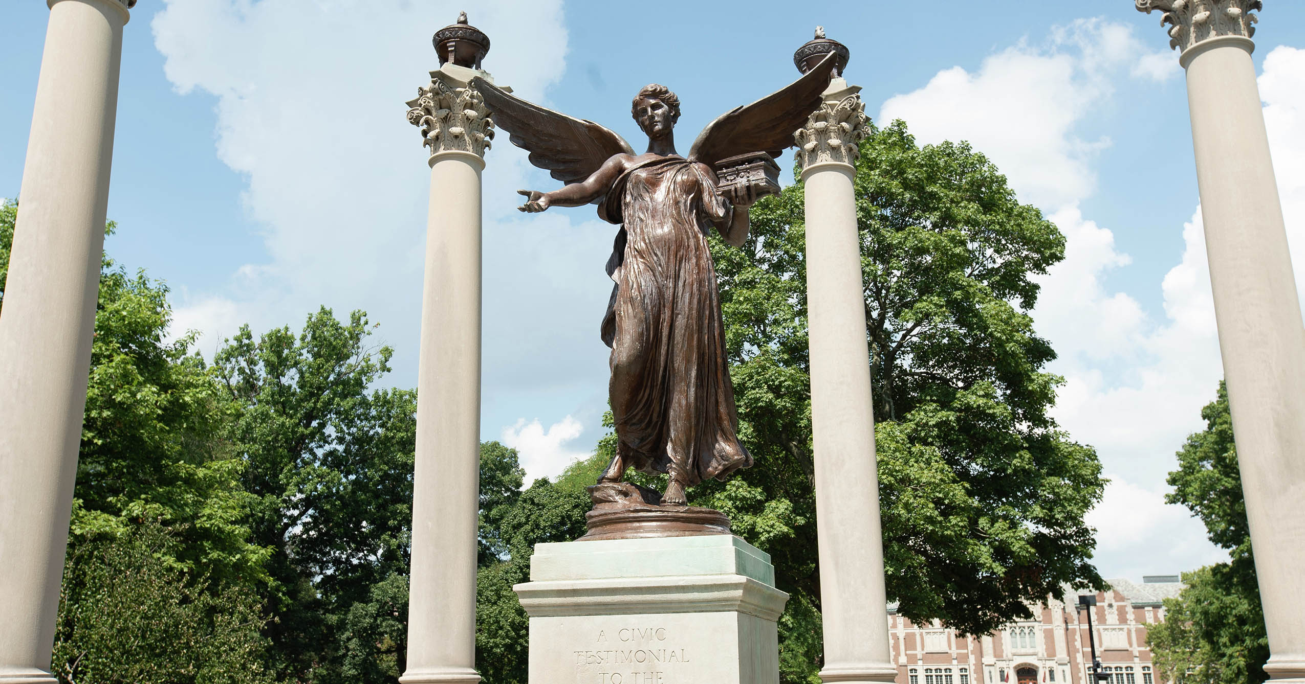 Ball State’s Beneficence statue framed by the monument’s columns on campus.