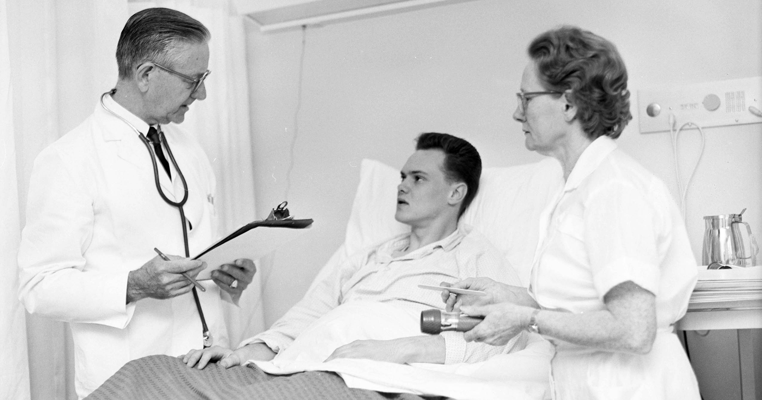 A physician and nurse attend to a patient in a bed at Ball State’s Amelia T. Wood Health Center in 1964.