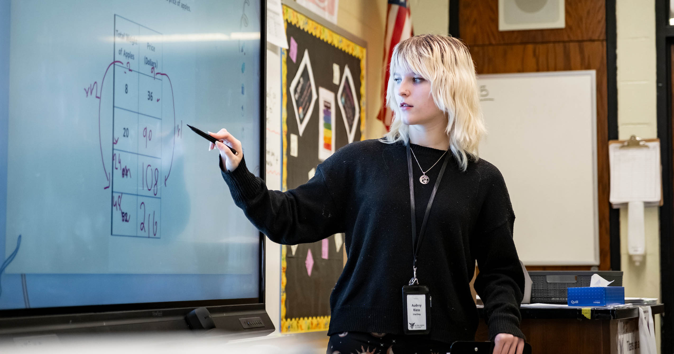 Ball State teacher candidate uses a stylus on an interactive classroom display during a math lesson.