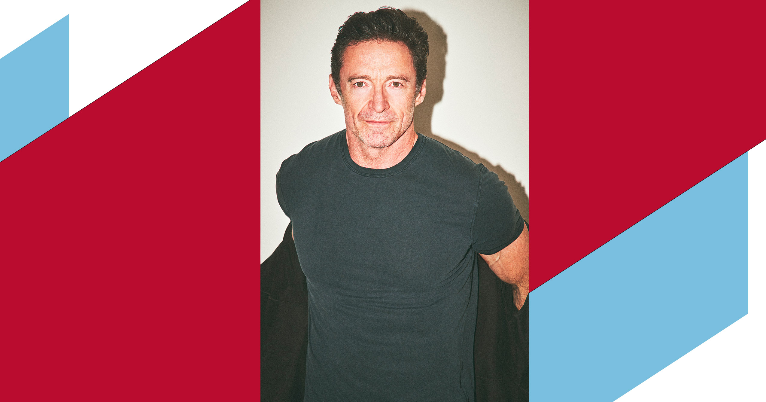 Hugh Jackman wearing a dark T-shirt, facing the camera with a slight smile against a plain background.