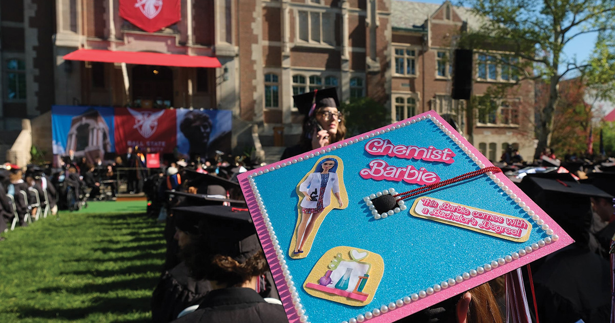 View from behind gratduates with mortar board in forground and stage in back