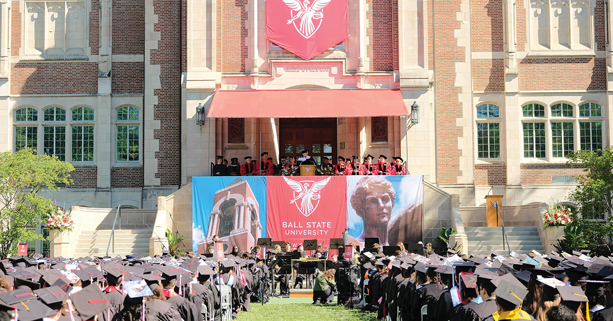View from behind graduates down center isle with stage at the end