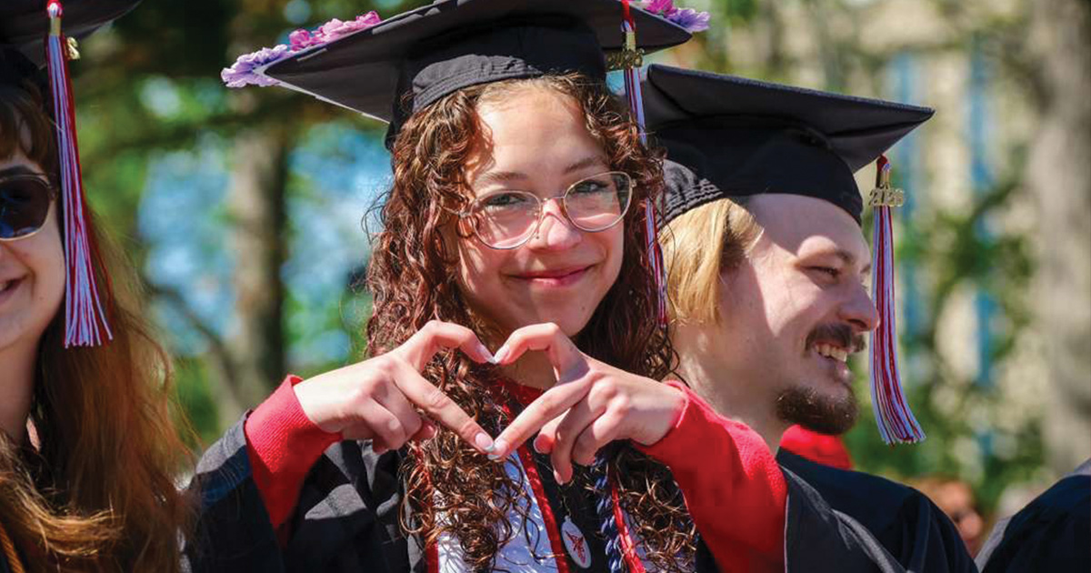 Graduate making heart-shaped hand gesture