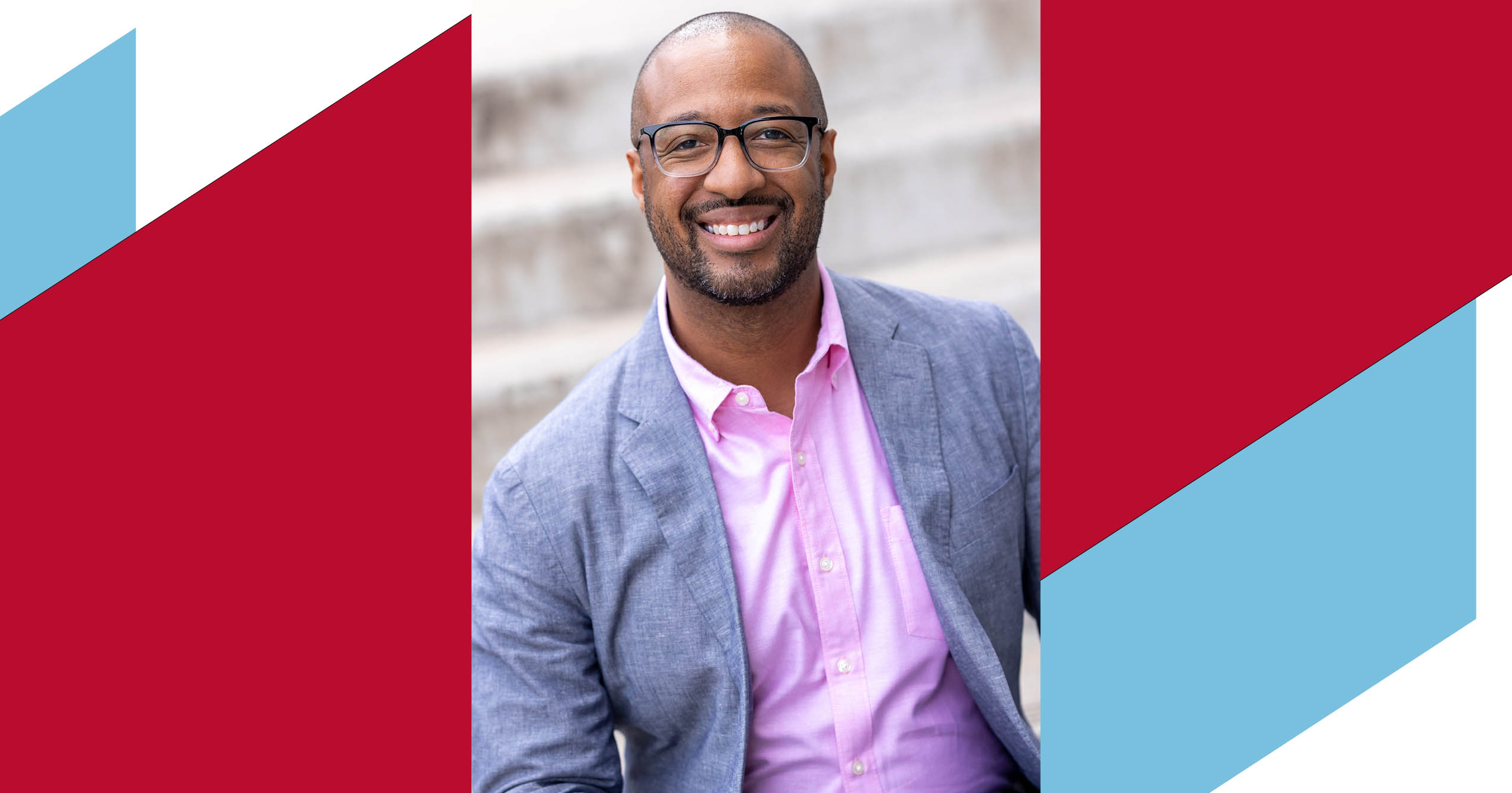 Portrait of author Varian Johnson smiling in glasses, a pink shirt, and a gray blazer.